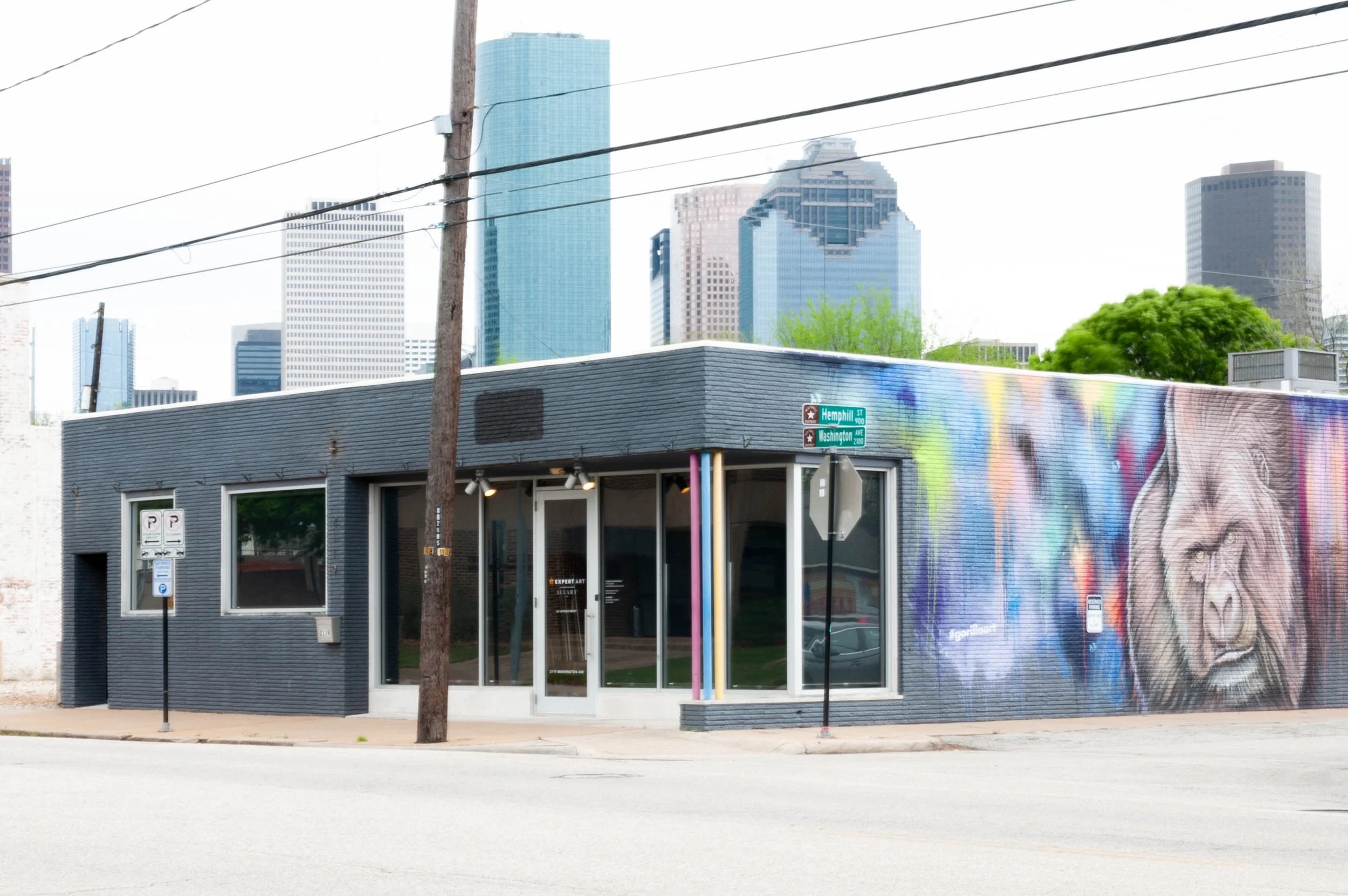 Allart's storefront at 2119 Washington Avenue, Houston, with the neighboring mural and downtown skyline behind it